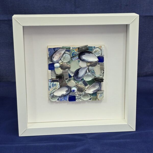 Glass mosaic in blue tones in white frame.