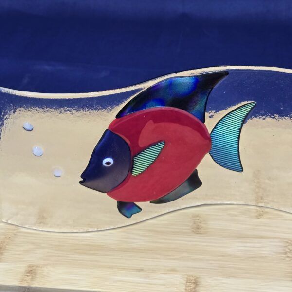 Red fish blowing three bubbles on wave shaped glass.