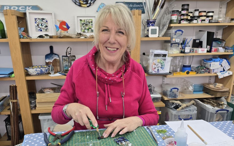 Julia Ford wearing pink hoodie working on mosaic.