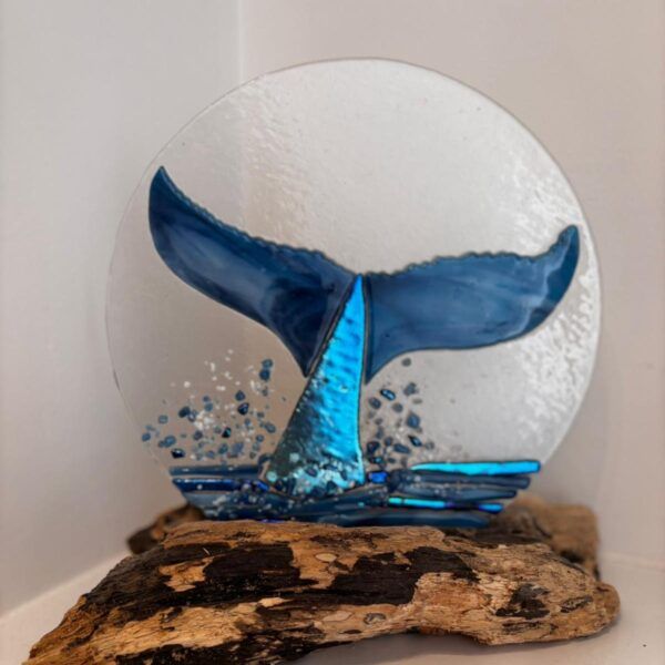 Glass creation depicting the tail of a whale diving into sea.